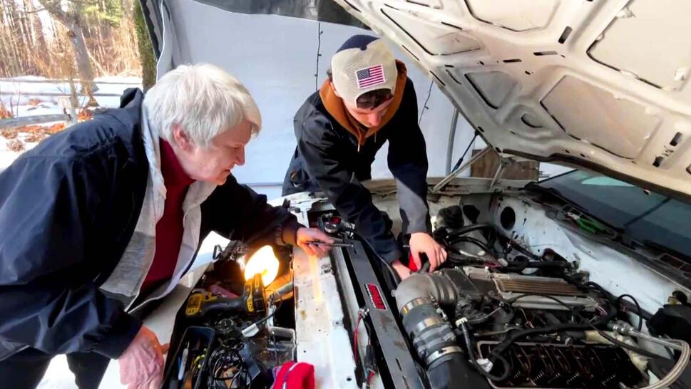 Grandmother and grandson working under hood of car